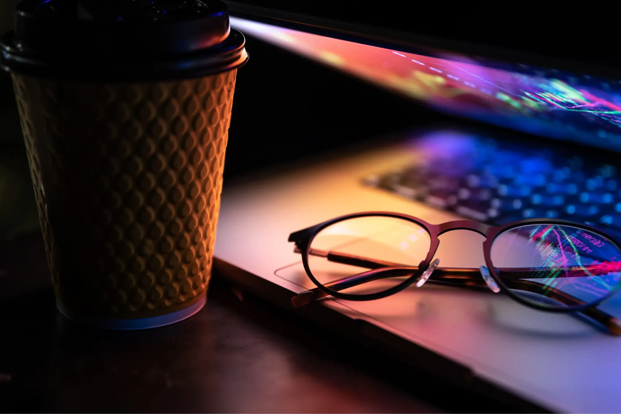 Home laptop half closed dark with colourful glow cup coffee glasses 2